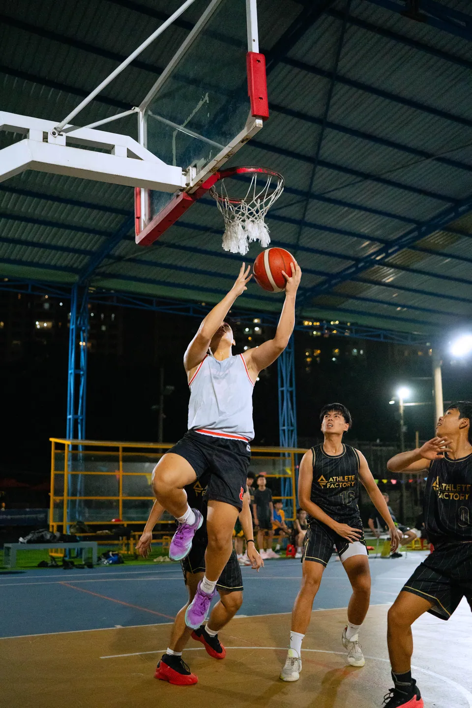 Outdoor basketball under floodlights at night