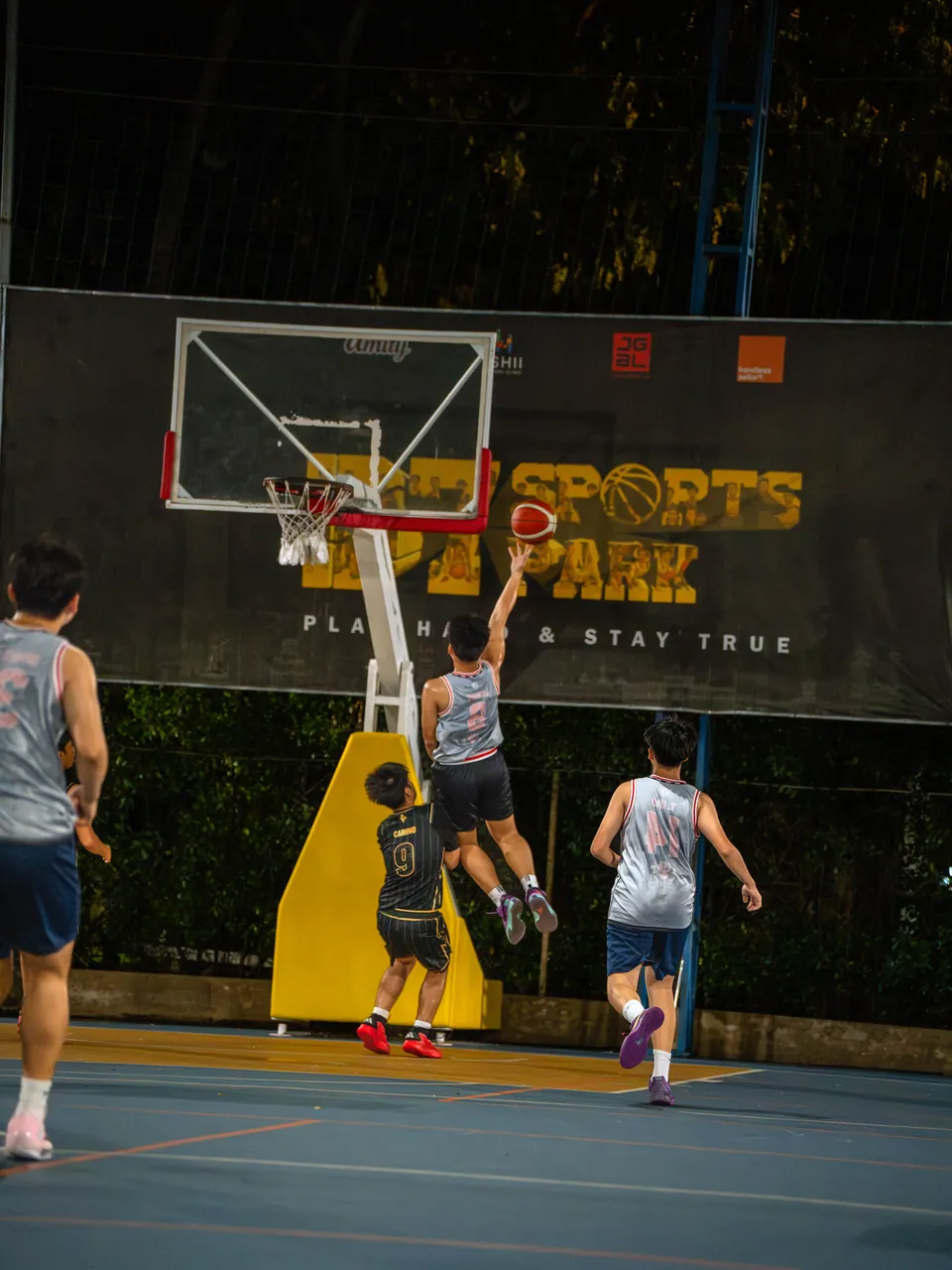 Outdoor basketball under floodlights at night