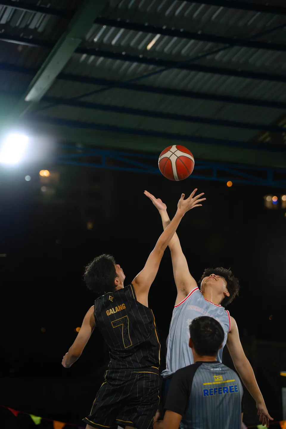 Outdoor basketball under floodlights at night