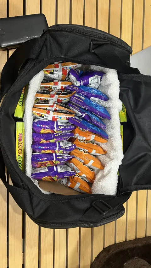 A duffel bag packed to the brim with Takis, Cheetos and boxes of Sour Patch Kids.