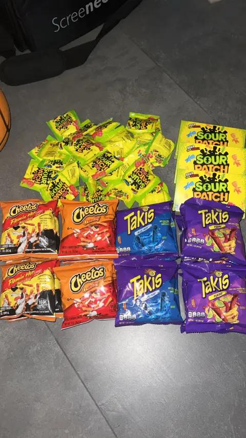 Stock laid out in rows on the floor - Takis Blue Heat and Fuego, Cheetos Crunchy and Flamin' Hot, and Sour Patch Kids.