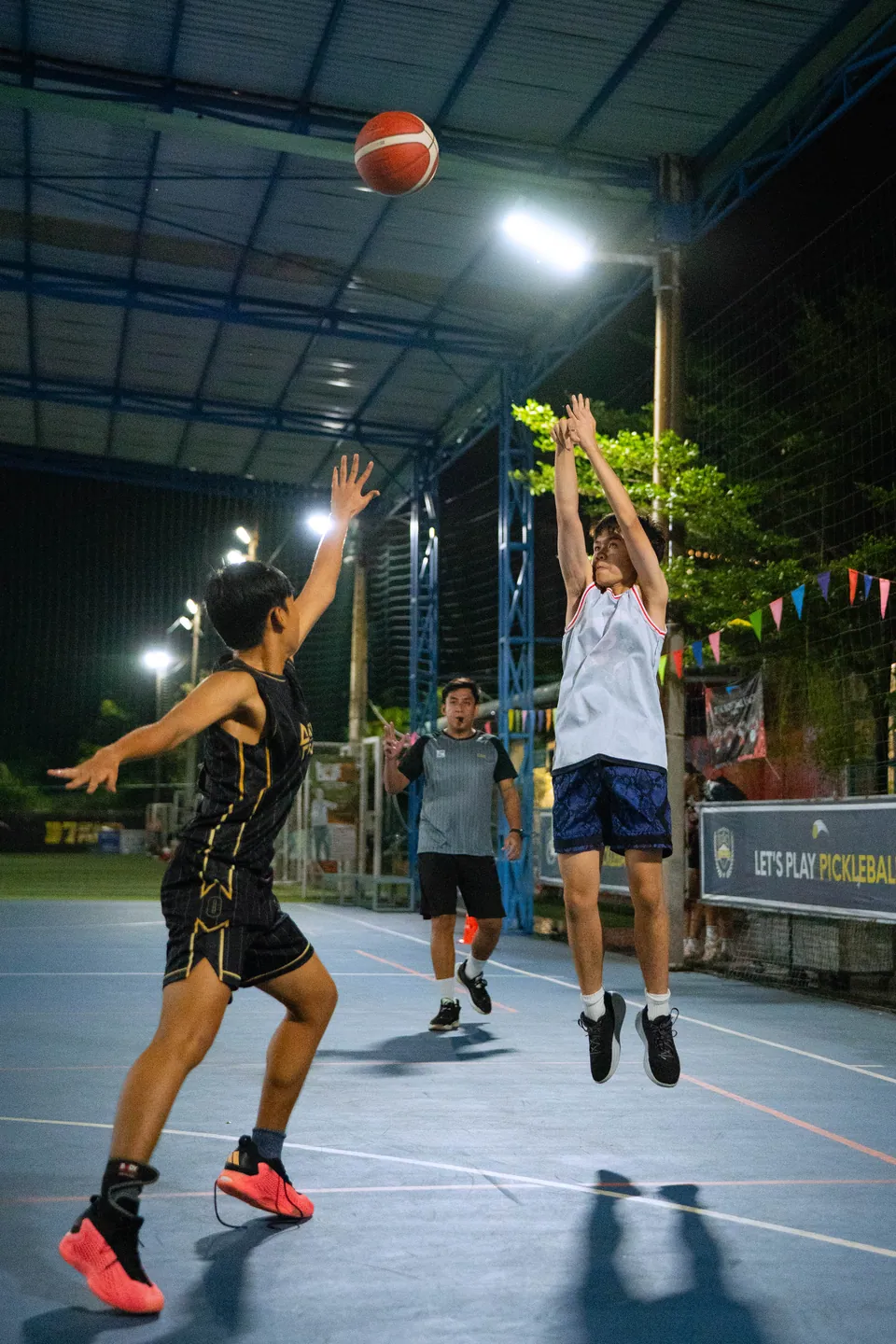 Outdoor basketball under floodlights at night