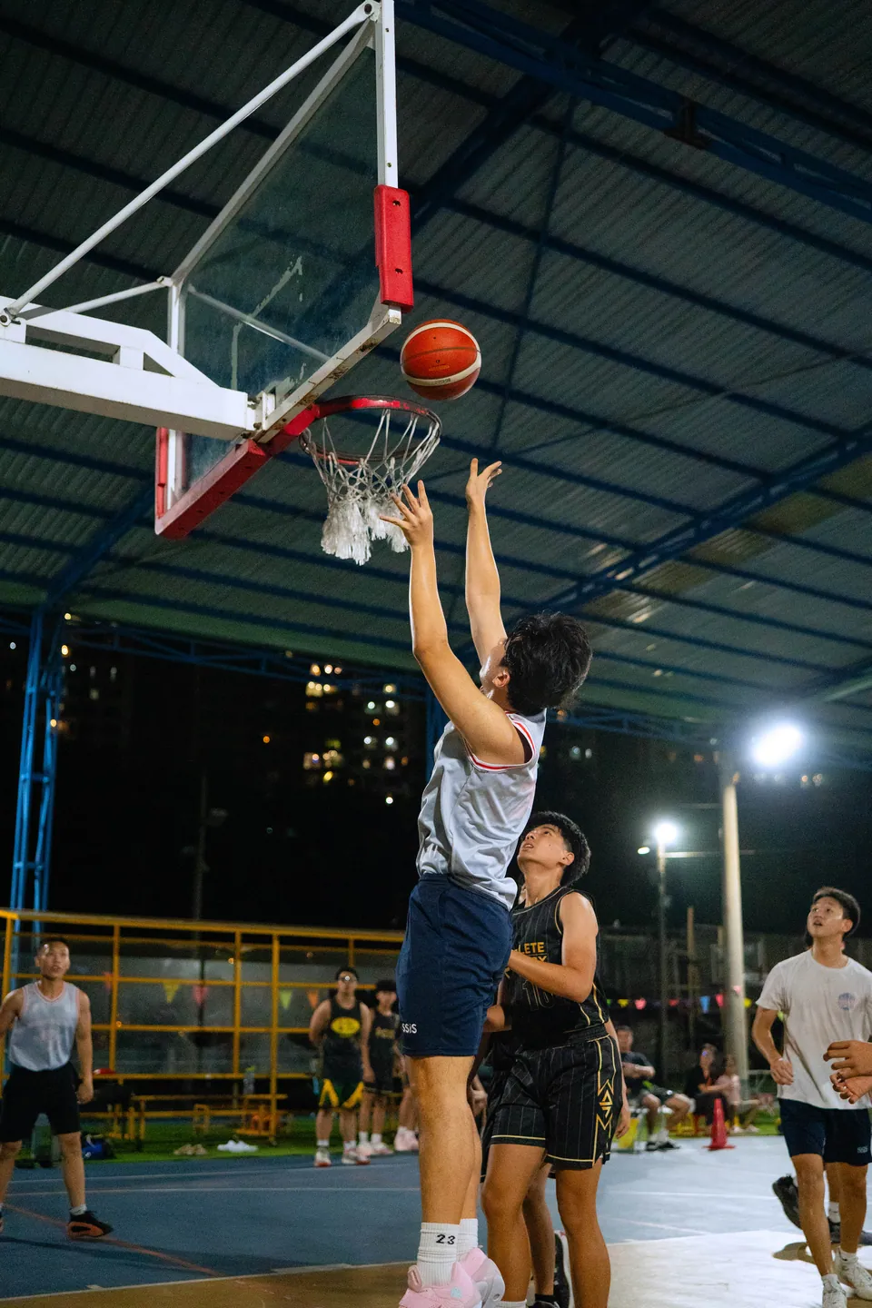 Outdoor basketball under floodlights at night