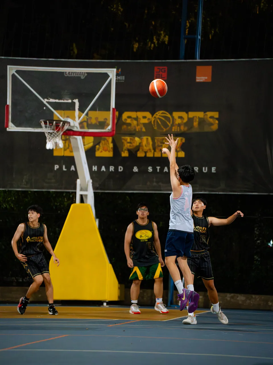 Outdoor basketball under floodlights at night