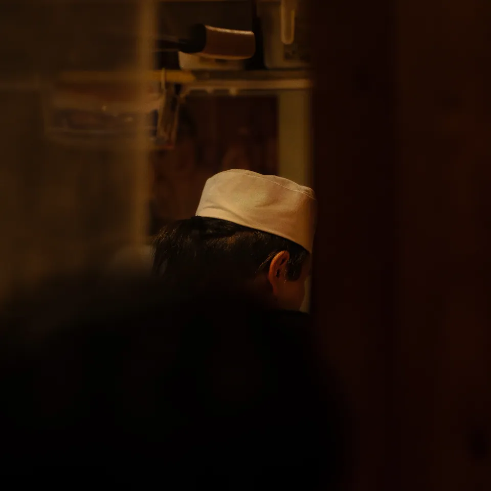 Person in a pale cap turned away, warm low light